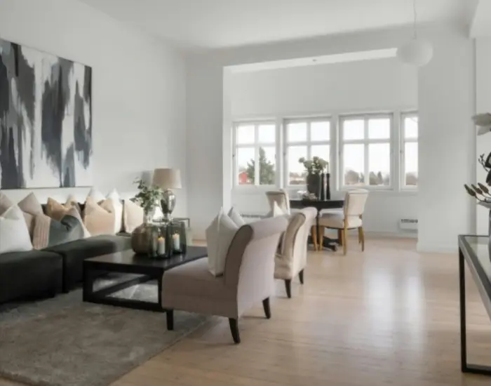Elegant living room with hardwood flooring, featuring modern furniture and large windows.